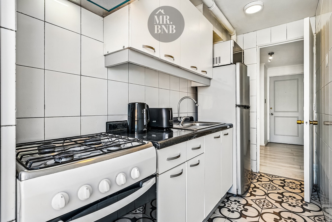 Cocina con cocina a gas, muebles blancos y piso decorado