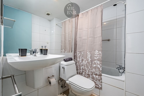 Baño con lavamanos, inodoro, tina con cortina y muro celeste