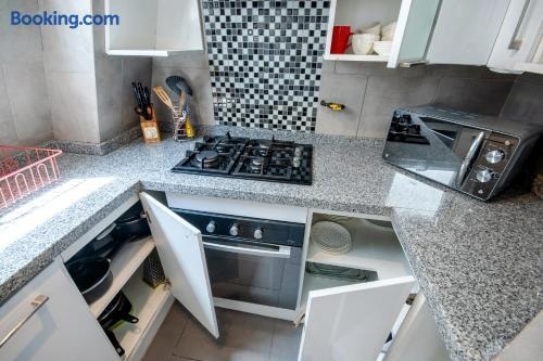 Cocina con encimera a gas, mosaico decorativo, horno y mesón de piedra con utensilios