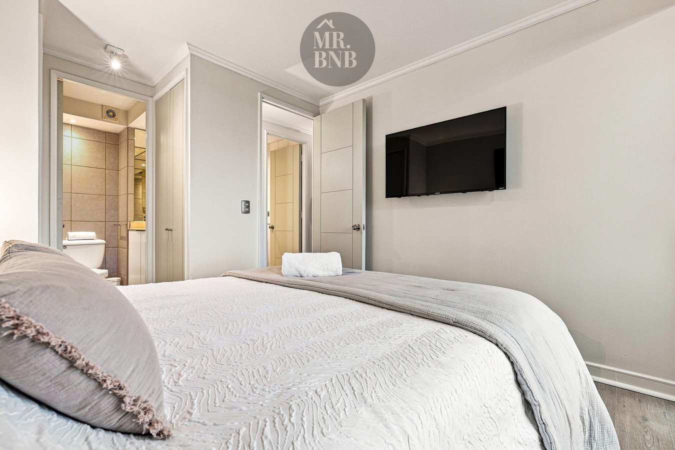 Dormitorio con cama, TV en la pared y puertas hacia otros ambientes