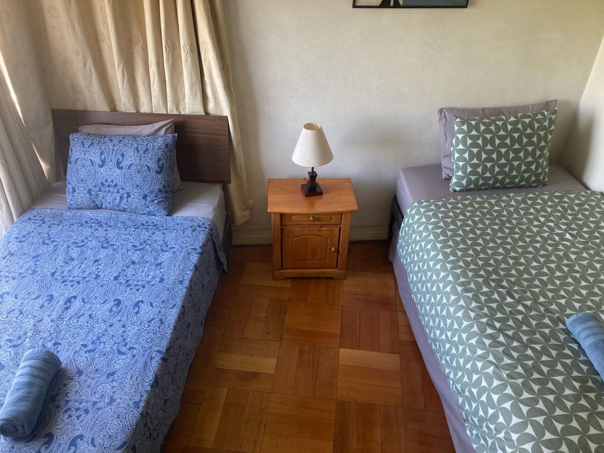 Dormitorio con dos camas individuales, veladores y lámpara