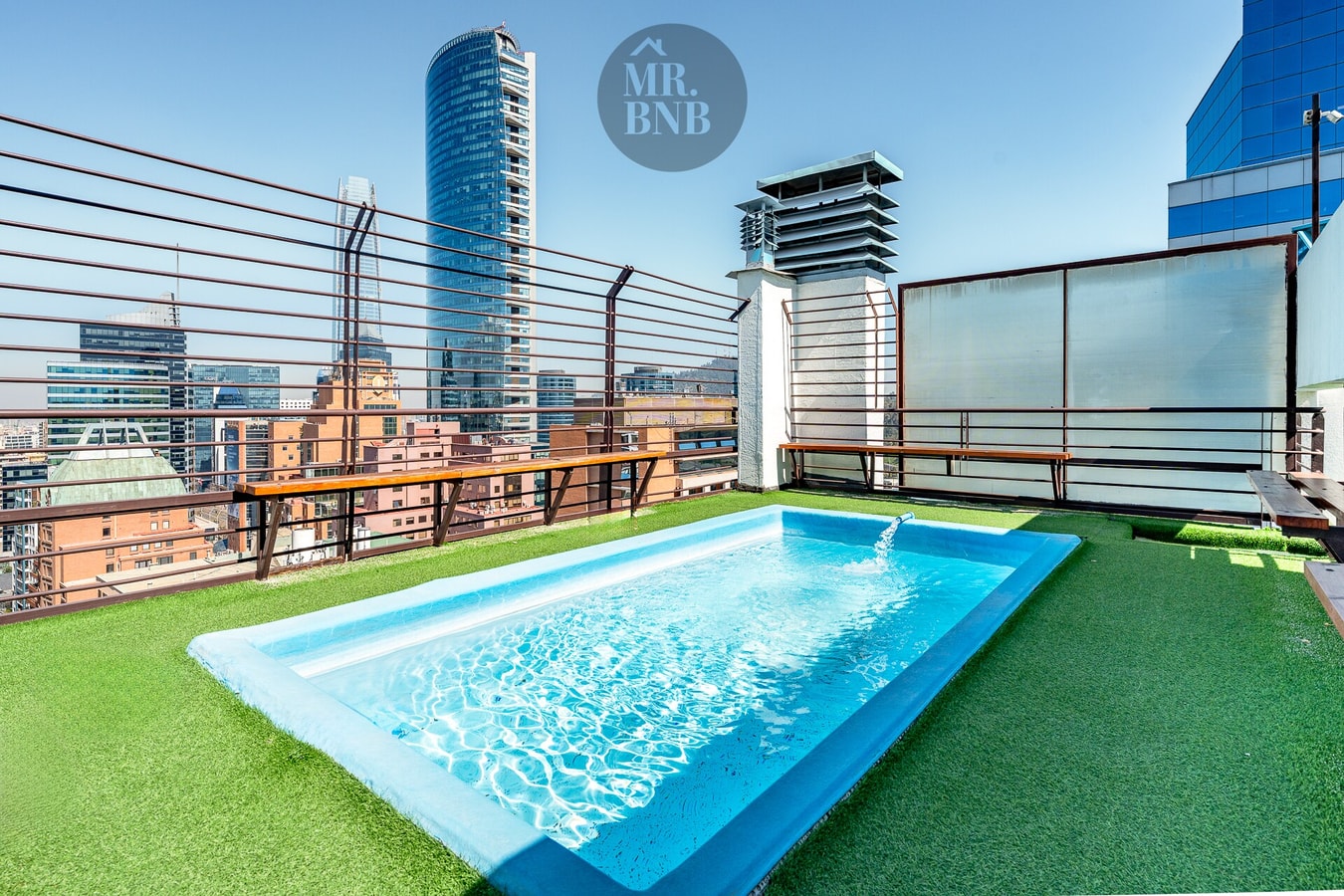 Piscina en azotea con pasto sintético, deck y vista a torres del sector
