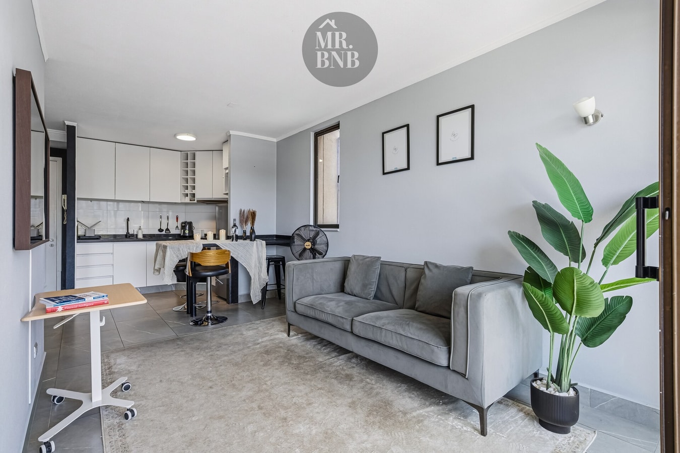 Living con sofá gris, planta, estantería y escritorio móvil