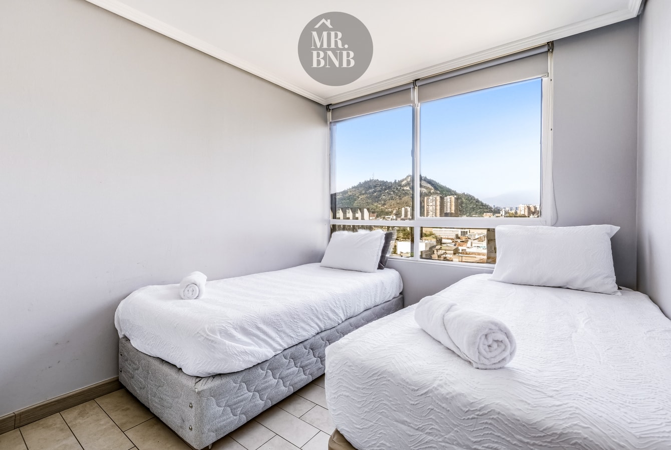 Dormitorio con dos camas individuales y ventanal con vista al cerro