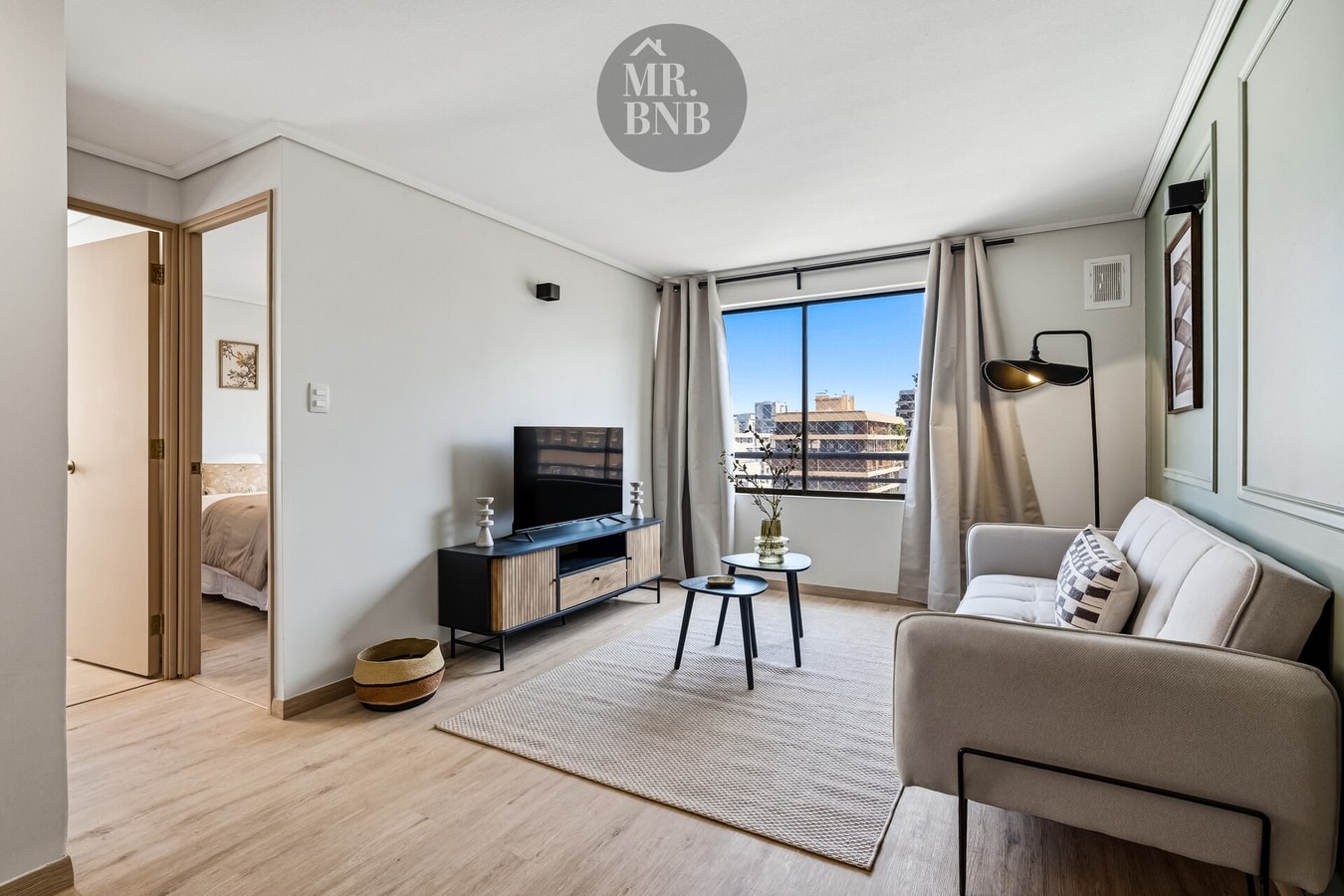Living con sofá, TV y vista al pasillo hacia un dormitorio