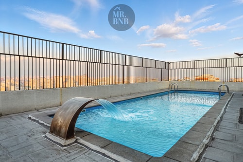 Piscina en azotea del edificio, con cascada decorativa y vista a la ciudad