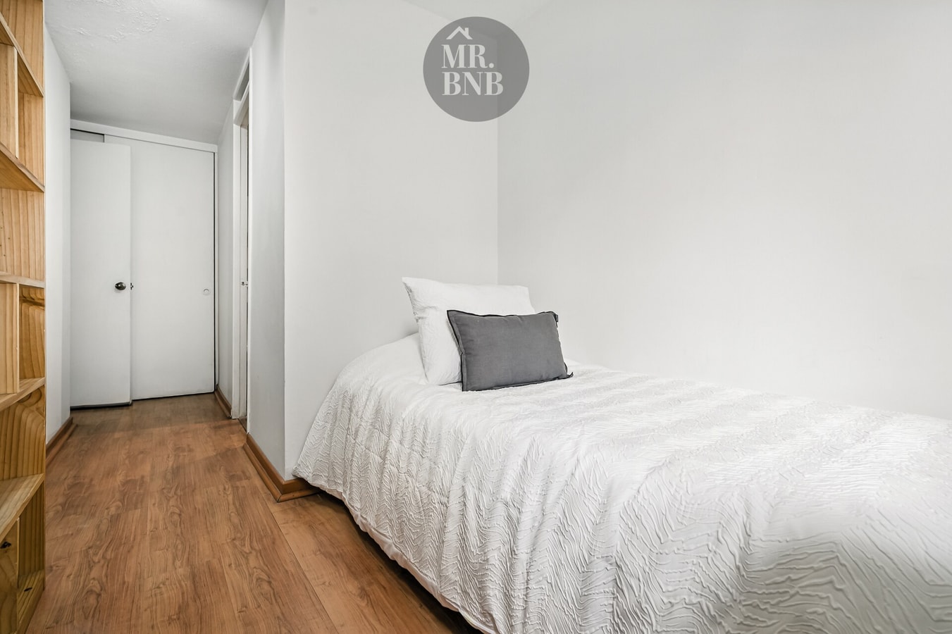 Dormitorio con cama individual y repisas de madera empotradas