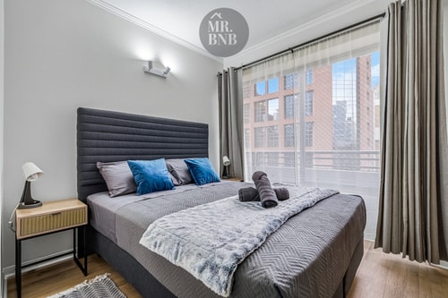 Dormitorio con cama, veladores, ventanal con vista y cortinas