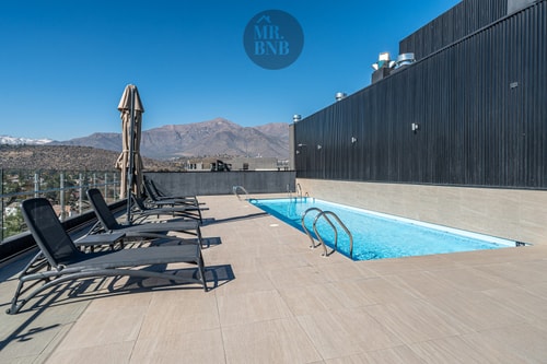 Piscina en azotea con reposeras, sombrilla y vista a la cordillera