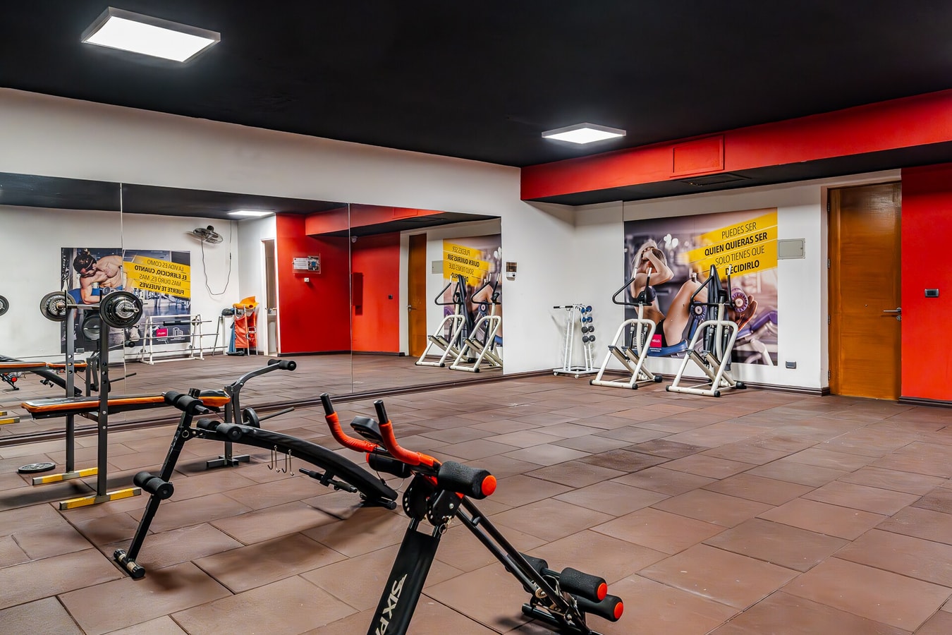 Gimnasio del edificio con máquinas de ejercicio, bicicleta y colchonetas