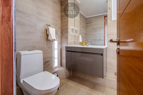 Baño con inodoro y mueble vanitorio, azulejo color arena