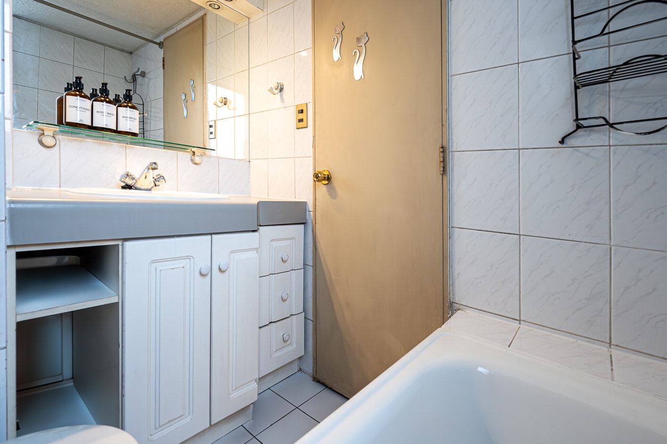 Baño con lavamanos, mueble bajo con cajones y bañera de tina revestida en cerámica clara.