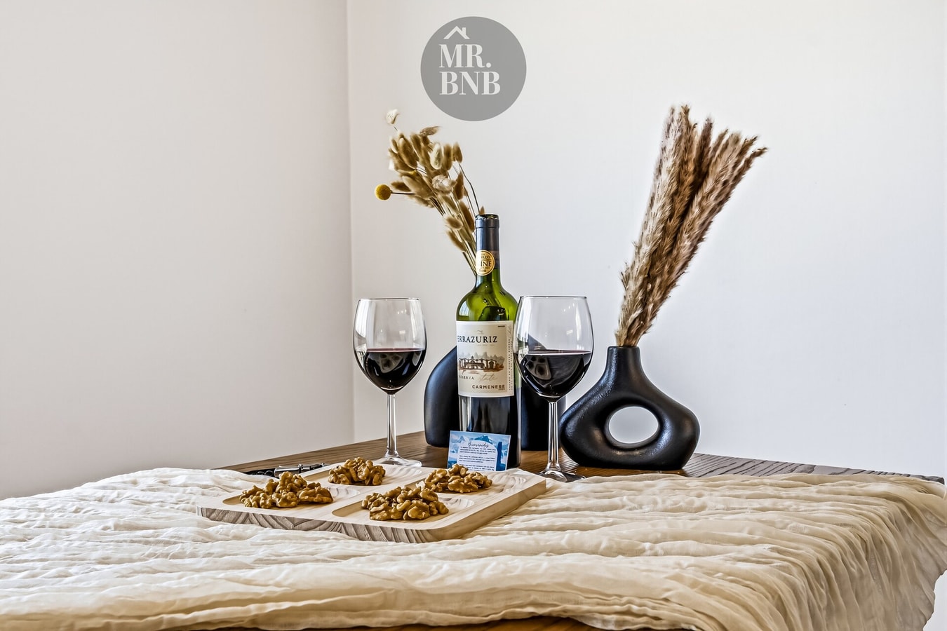 Detalle de cama con bandeja, copas de vino y decoración de bienvenida