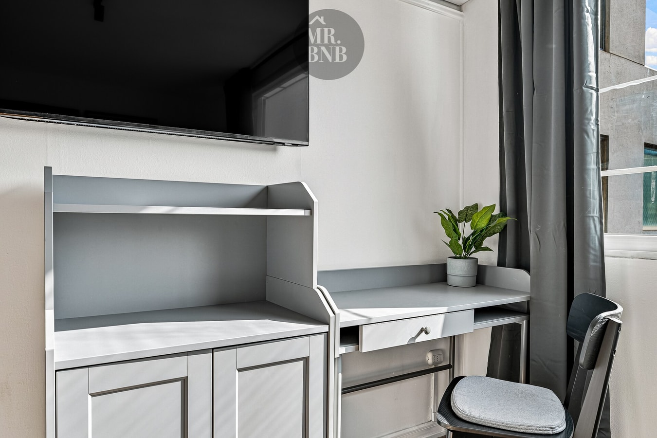Detalle de escritorio con repisas y silla, ventanal con cortina oscura