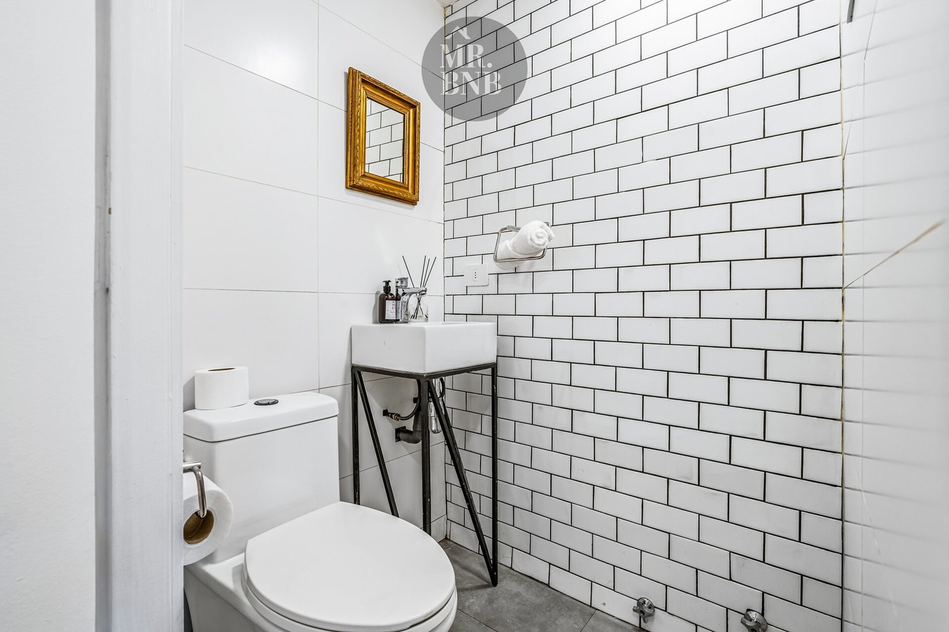 Baño con azulejo blanco tipo metro, lavamanos y WC