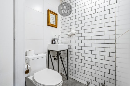 Baño con azulejo blanco tipo metro, lavamanos y WC