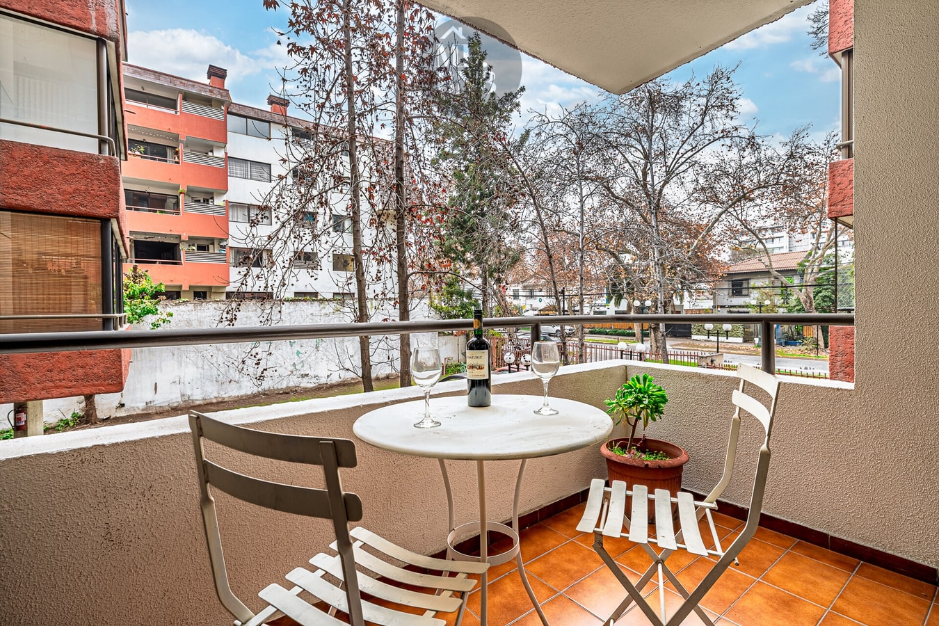 Terraza privada con mesa redonda, sillas y vista al jardín del edificio