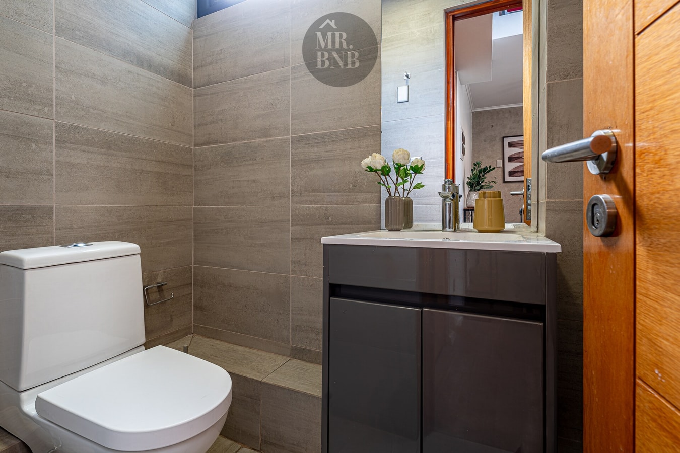 Baño con WC, mueble vanitorio y flores decorativas