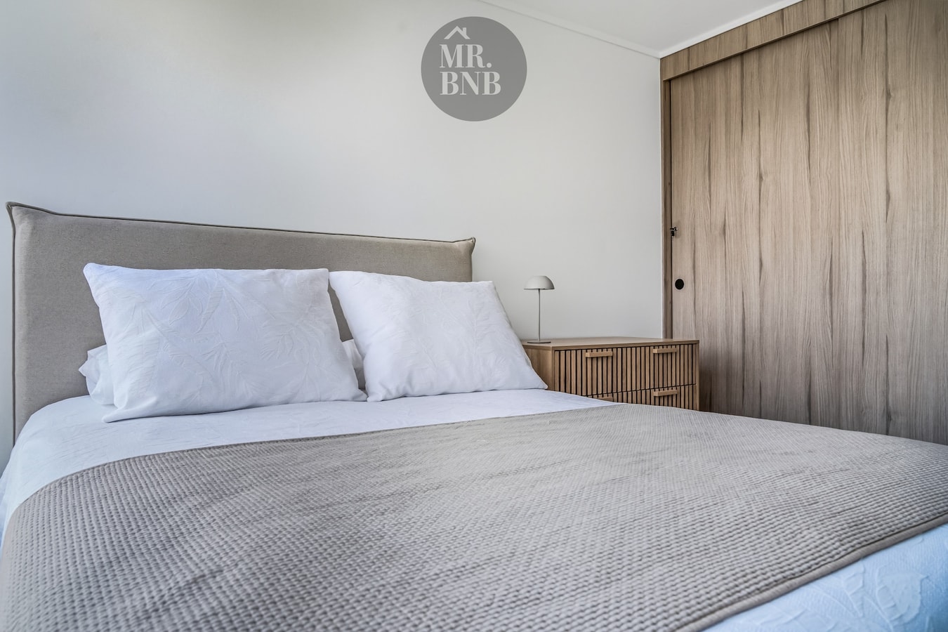 Dormitorio con cama doble, respaldo tapizado y closet de madera