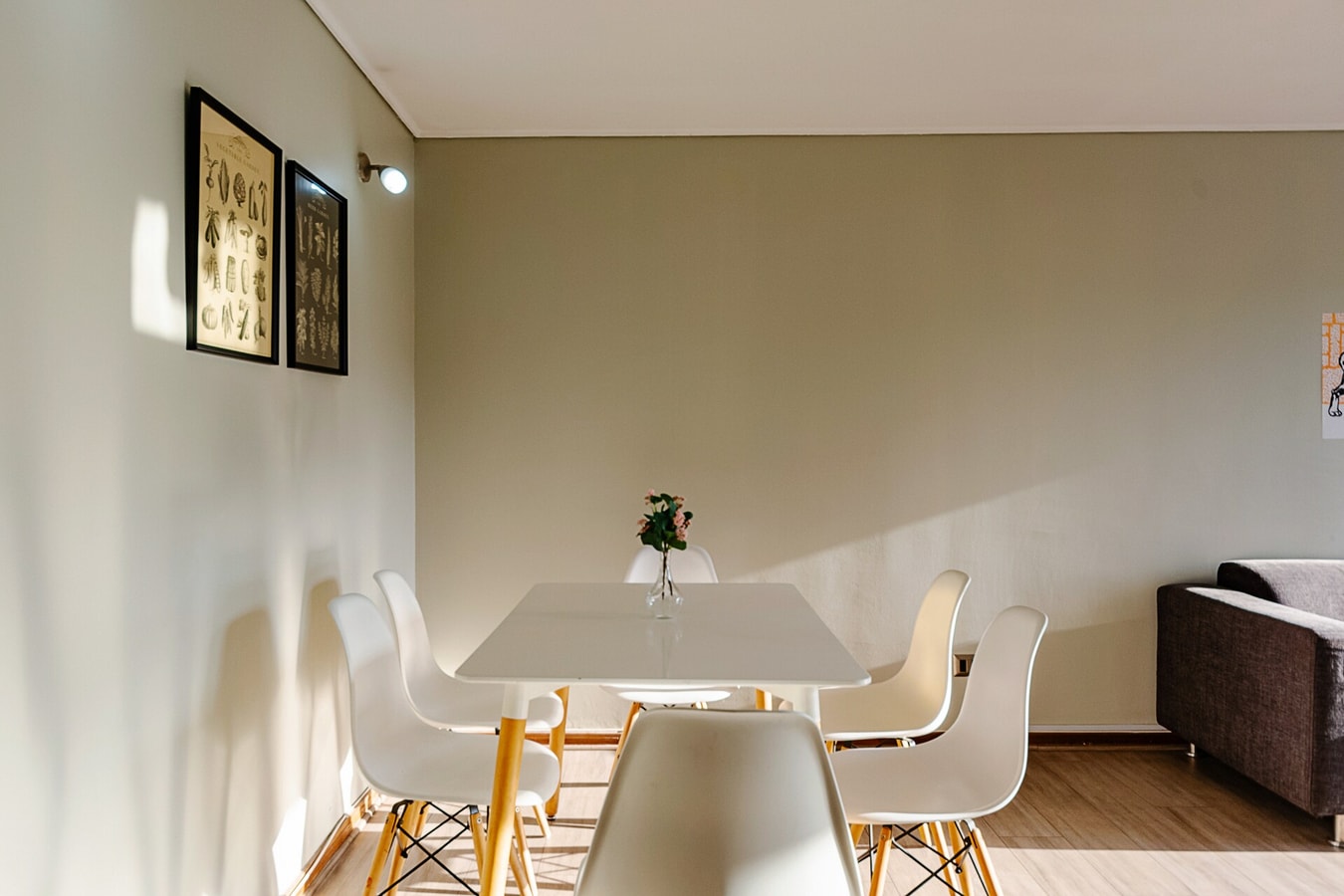 Comedor con mesa blanca, sillas y cuadros en la pared.