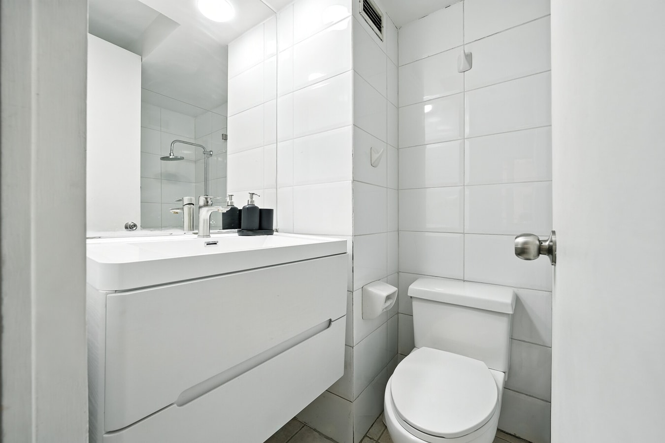 Baño con mueble vanitorio blanco, espejo e inodoro