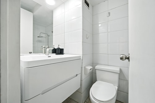 Baño con mueble vanitorio blanco, espejo e inodoro