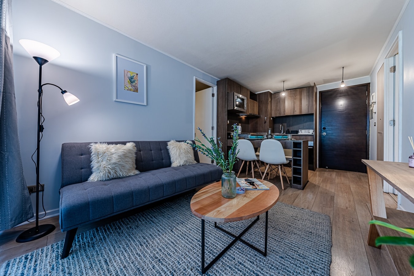 Living con sofá azul, mesa de centro y cocina abierta