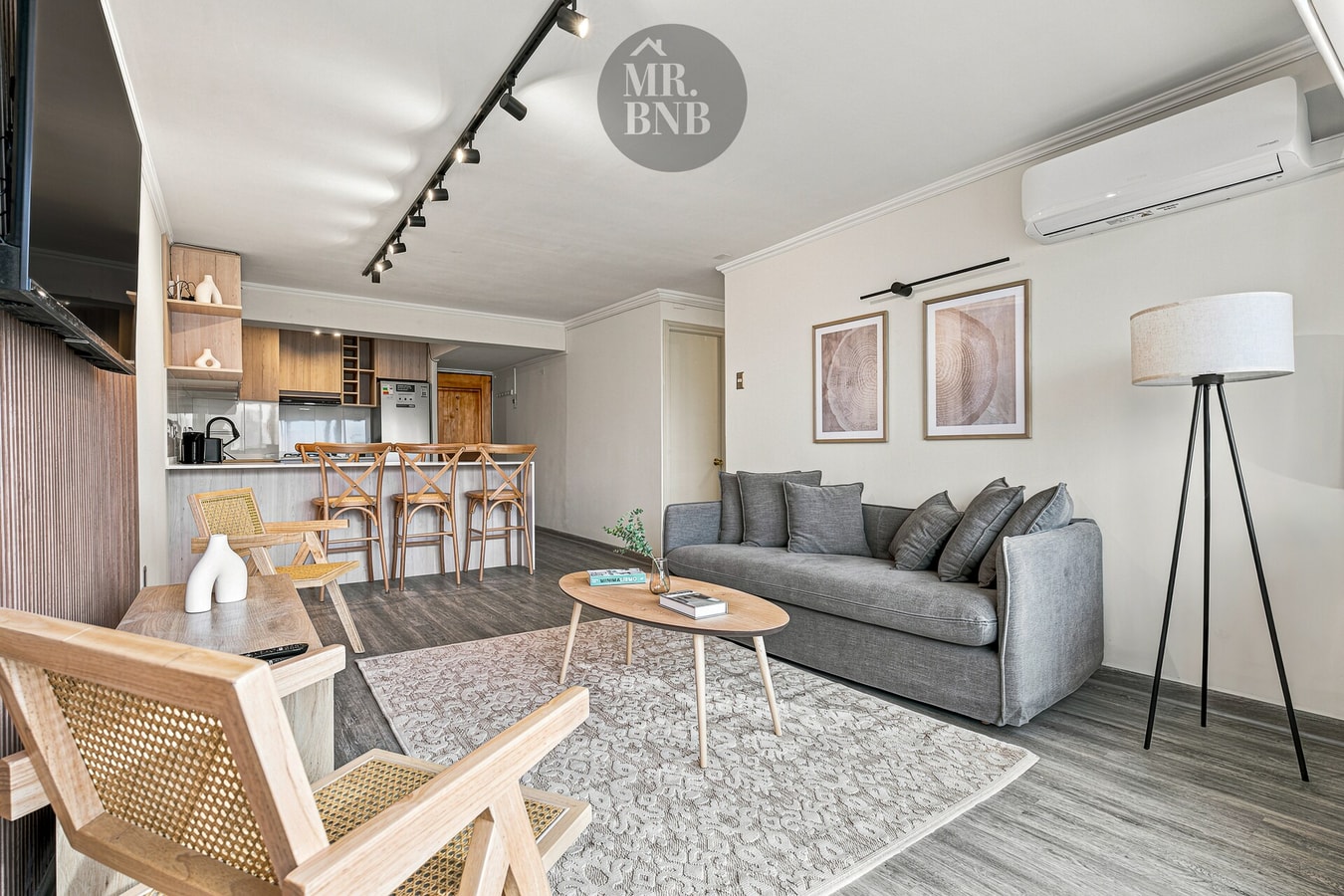 Living con sofá gris, sillón, aire acondicionado de pared y cuadros decorativos.