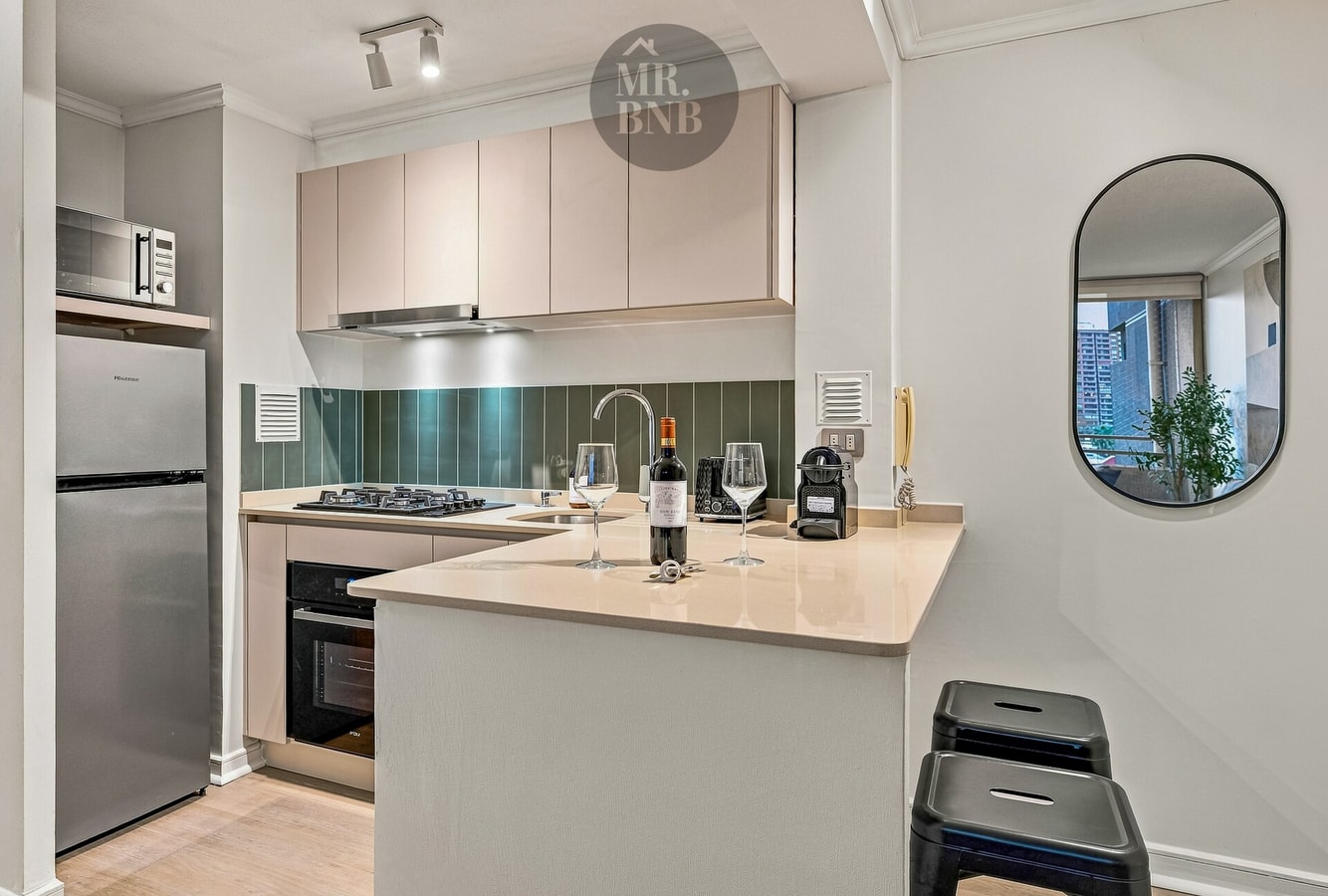 Cocina americana con barra, campana, refrigerador, cocina a gas y espejo ovalado
