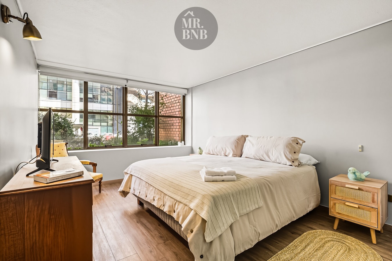 Dormitorio con cama de dos plazas, escritorio de madera y ventana