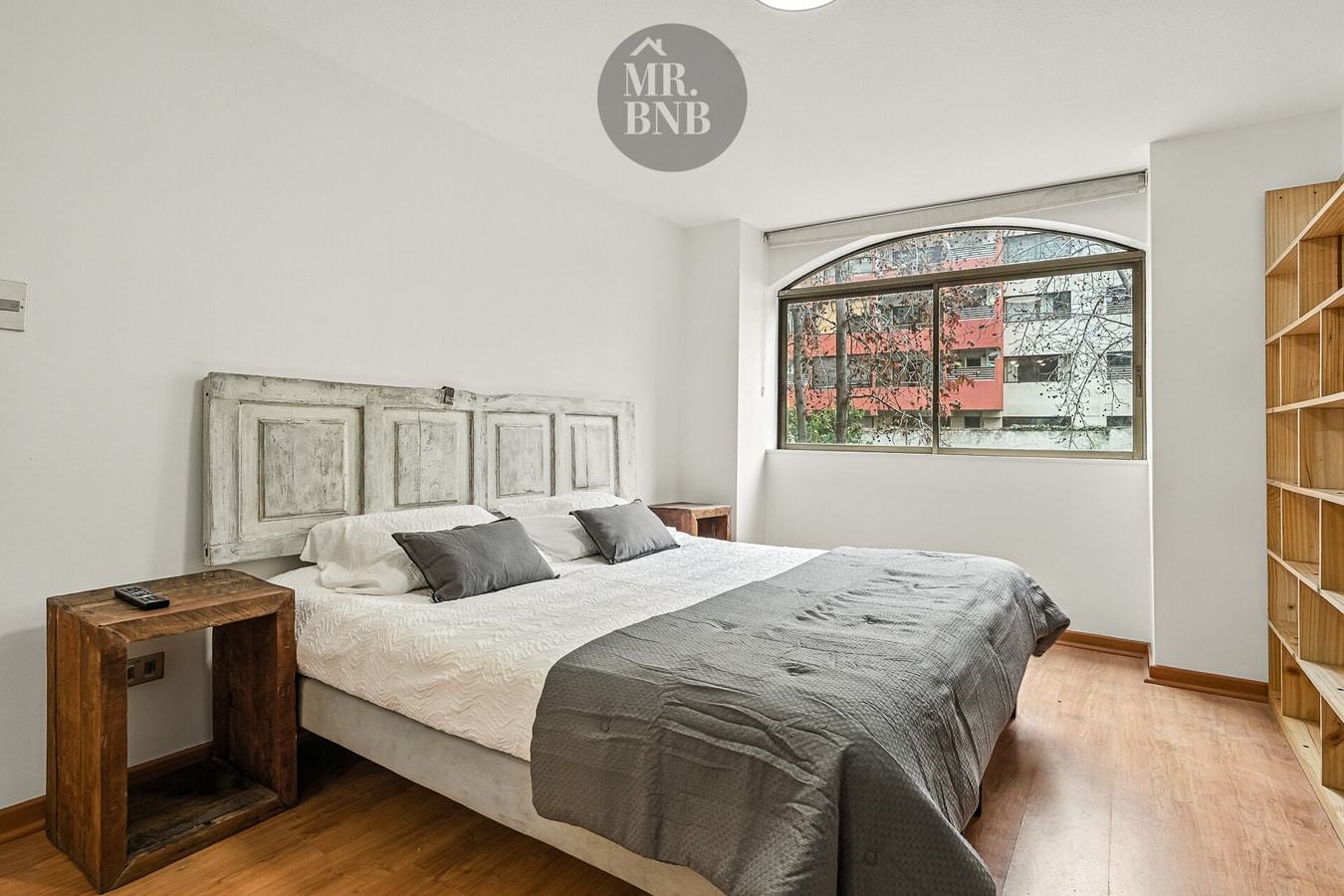 Dormitorio con cama matrimonial, cabecero de madera tallada y repisas