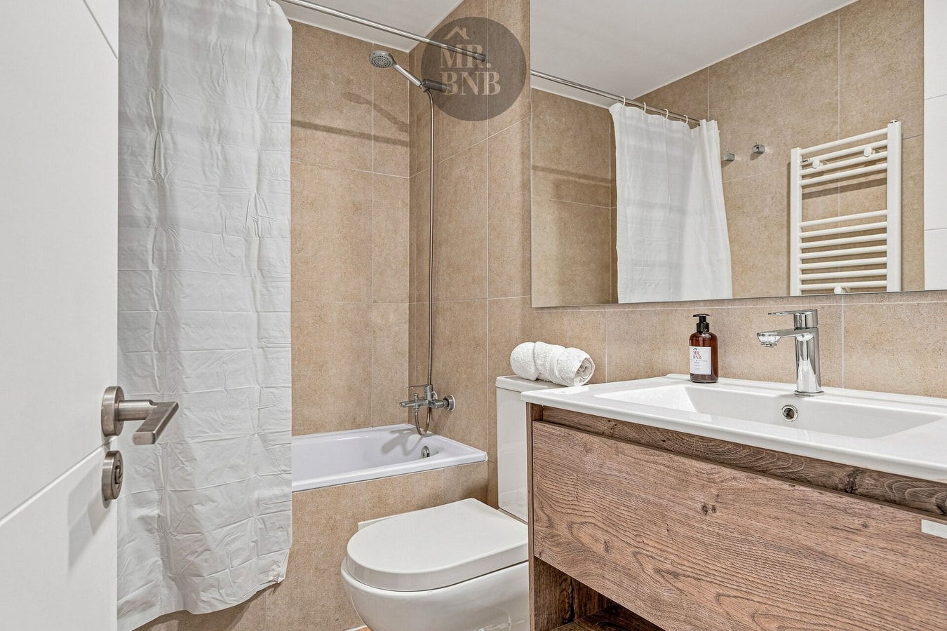 Baño con tina, cortina, toallero y mueble vanitorio de madera