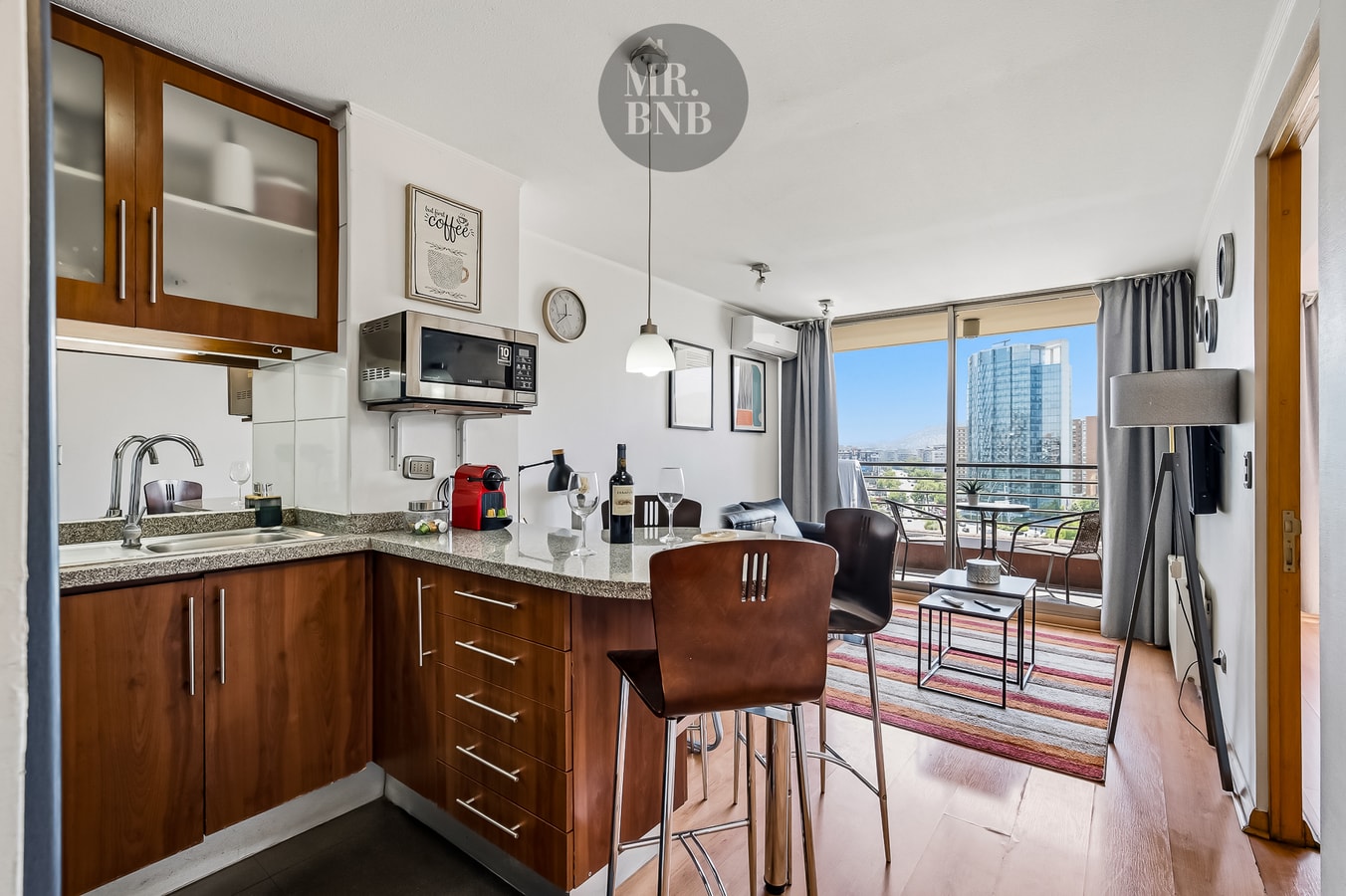 Cocina equipada con encimera, microondas y barra alta con vista a la ciudad desde el living.