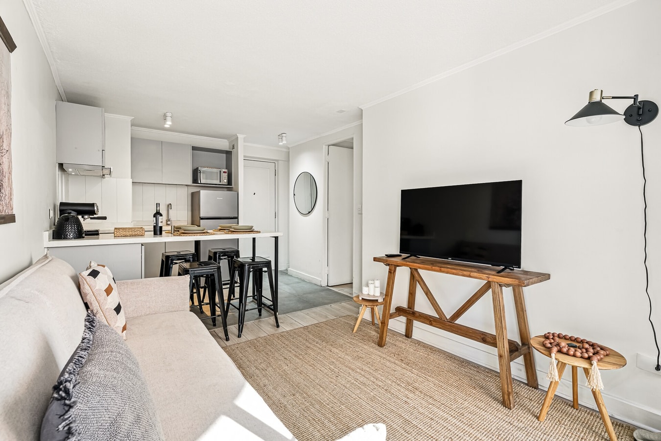 Living con sofá, mesa auxiliar de madera, televisor y cocina al fondo