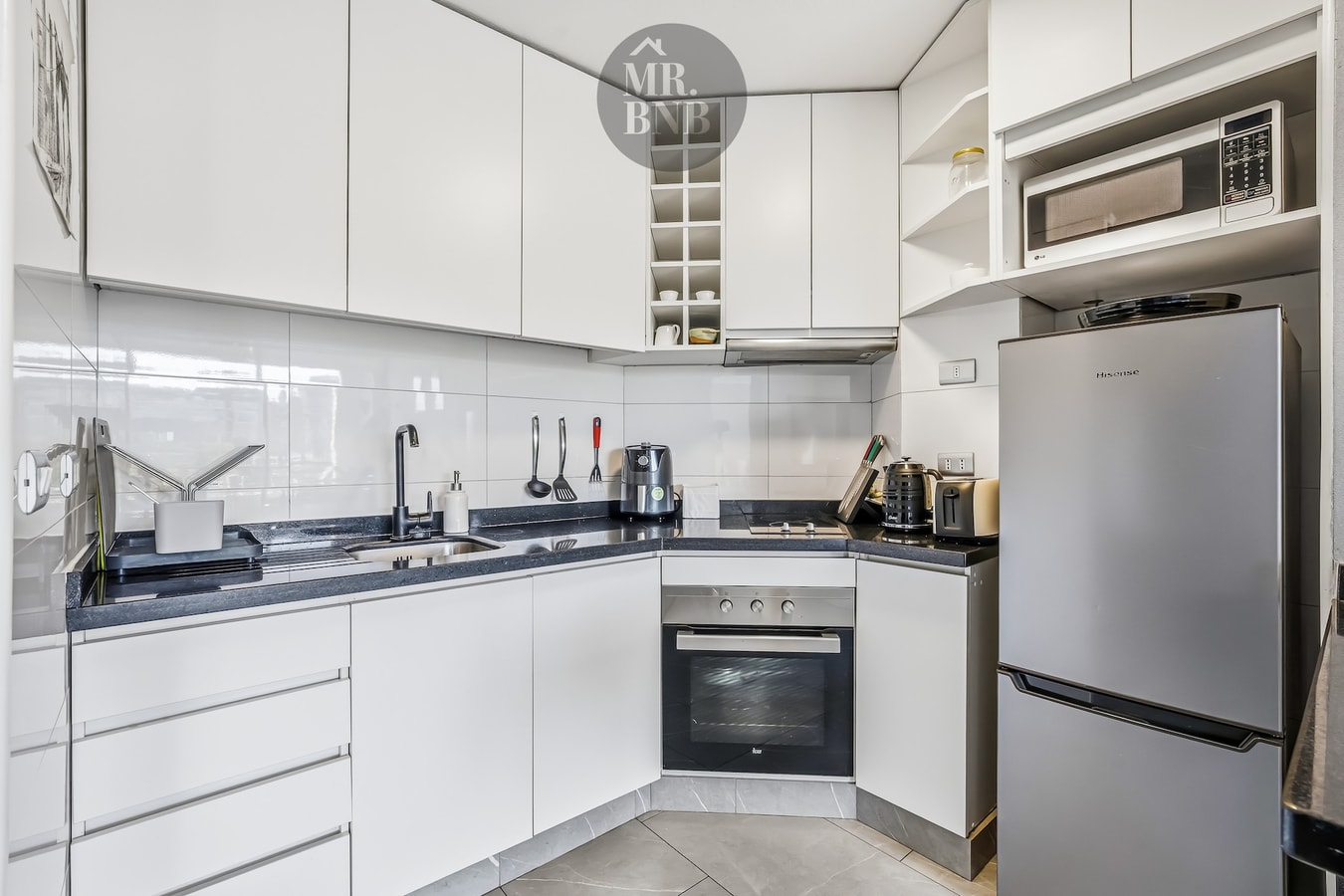 Cocina en L blanca con horno, refrigerador y microondas