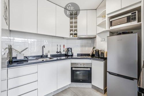 Cocina en L blanca con horno, refrigerador y microondas