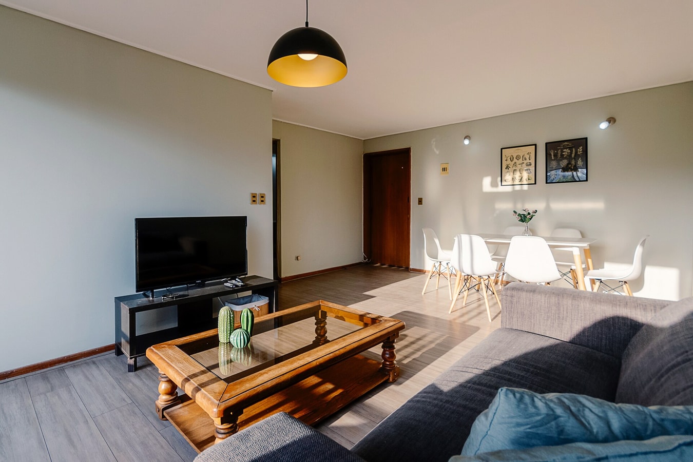 Living con sofá gris, televisor y mesa de centro de madera.