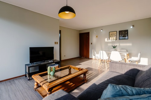 Living con sofá gris, televisor y mesa de centro de madera.
