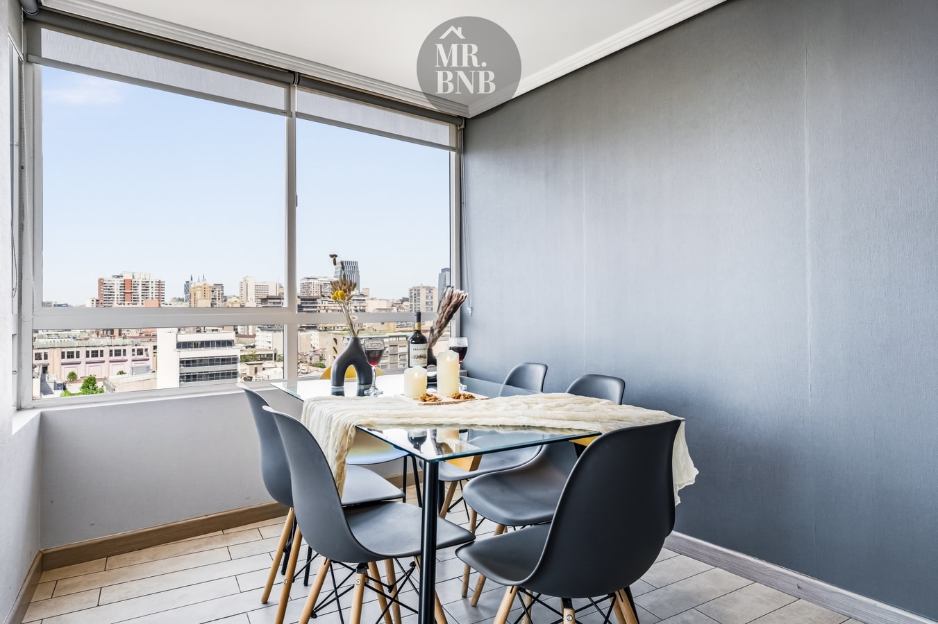 Comedor con mesa de vidrio, sillas negras y ventanal con vista a la ciudad