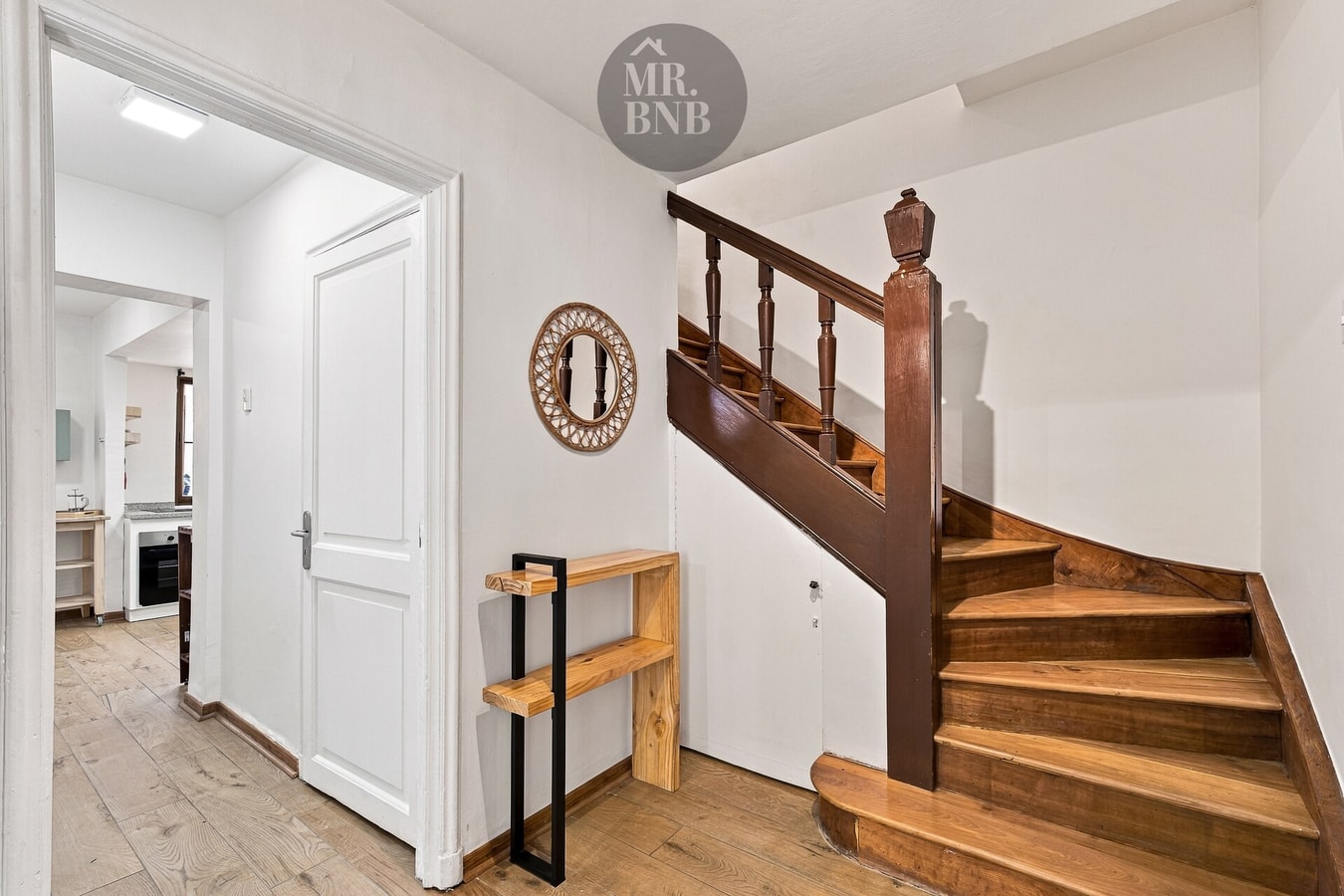 Hall de entrada con escalera de madera al segundo piso y puerta.