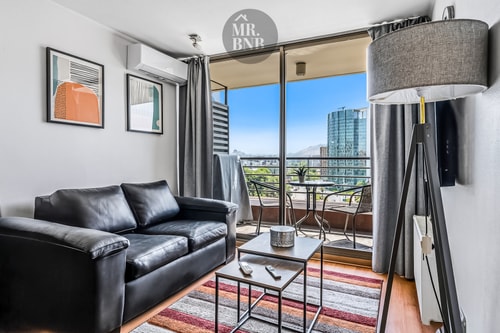 Living con sofá negro, mesa de centro y ventanal hacia la terraza con vista a la ciudad.
