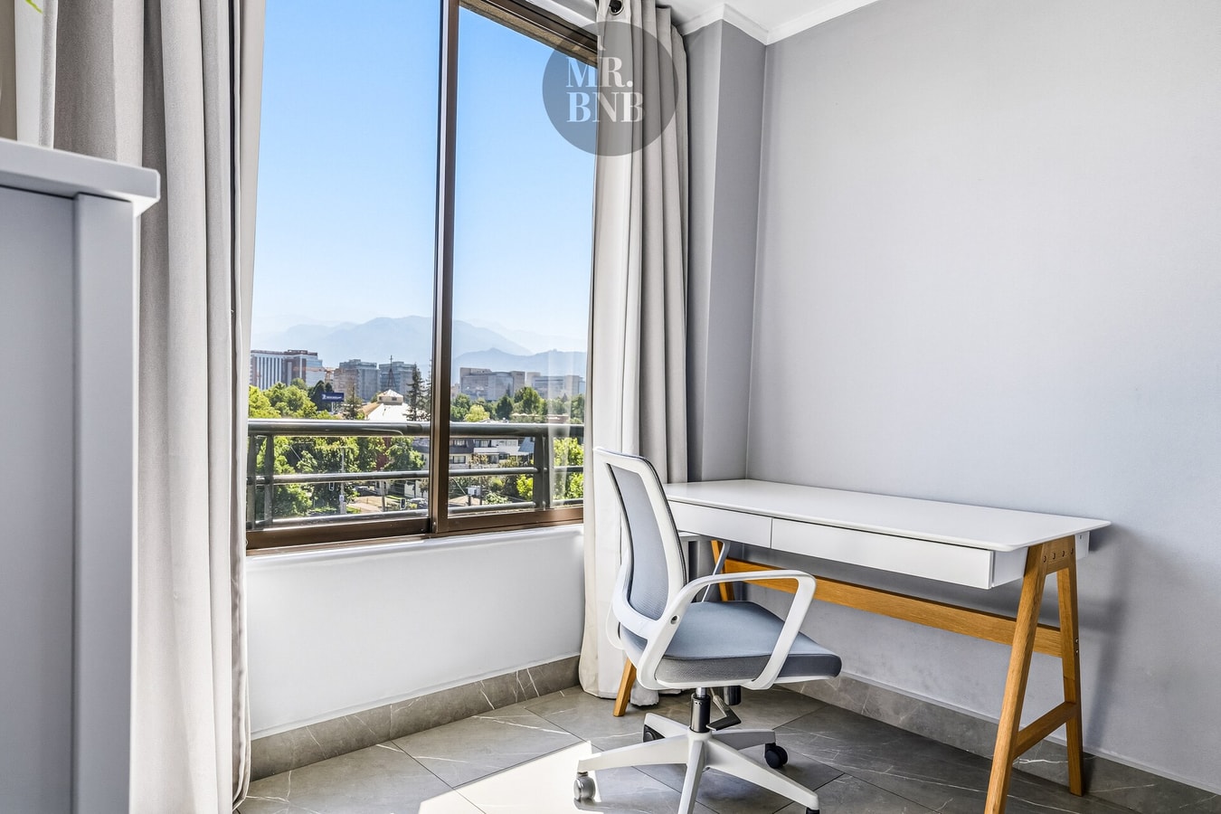 Escritorio junto a ventana con vista panorámica a la cordillera y silla ergonómica