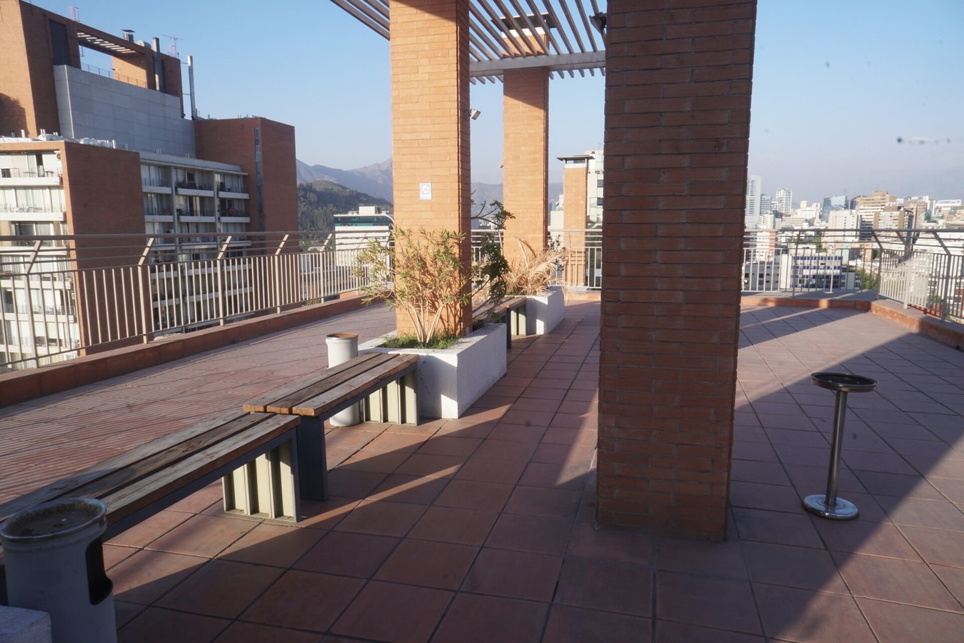 Terraza de la azotea con pérgola de madera, bancas, jardineras y vista a la ciudad y la cordillera