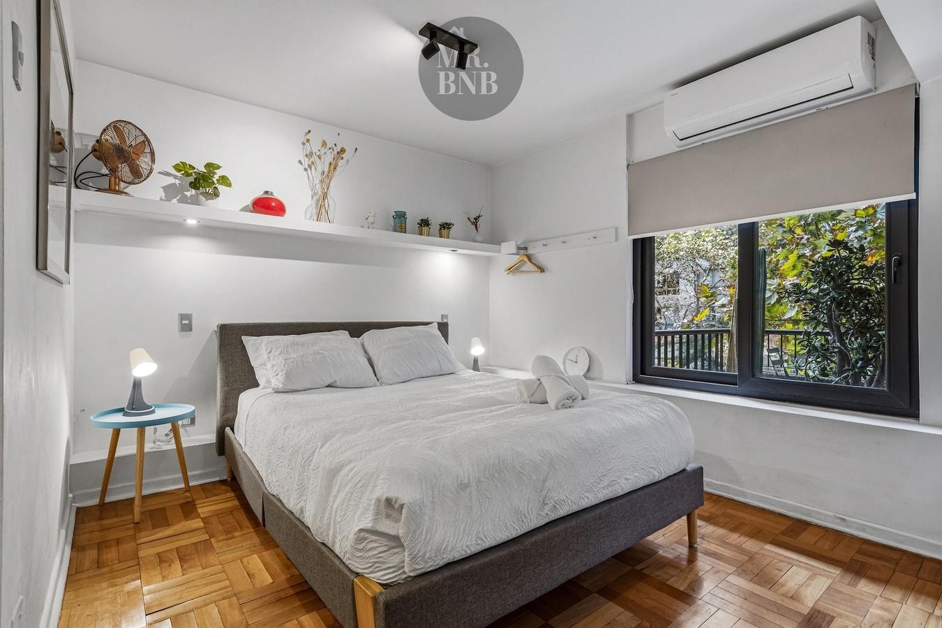 Dormitorio de suite con cama, aire acondicionado y repisa decorativa