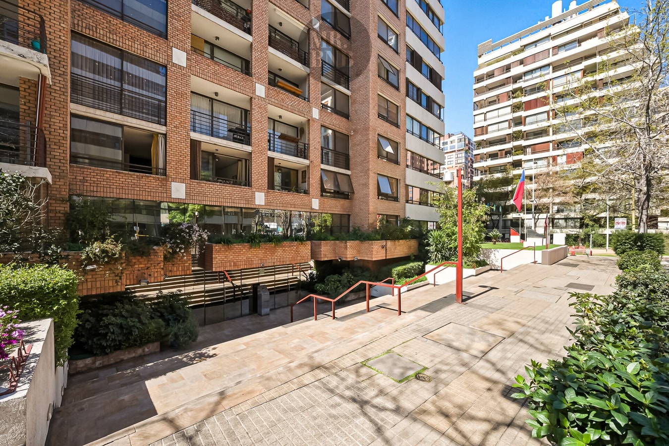 Fachada y patio de acceso del edificio, con jardineras y sendero de entrada