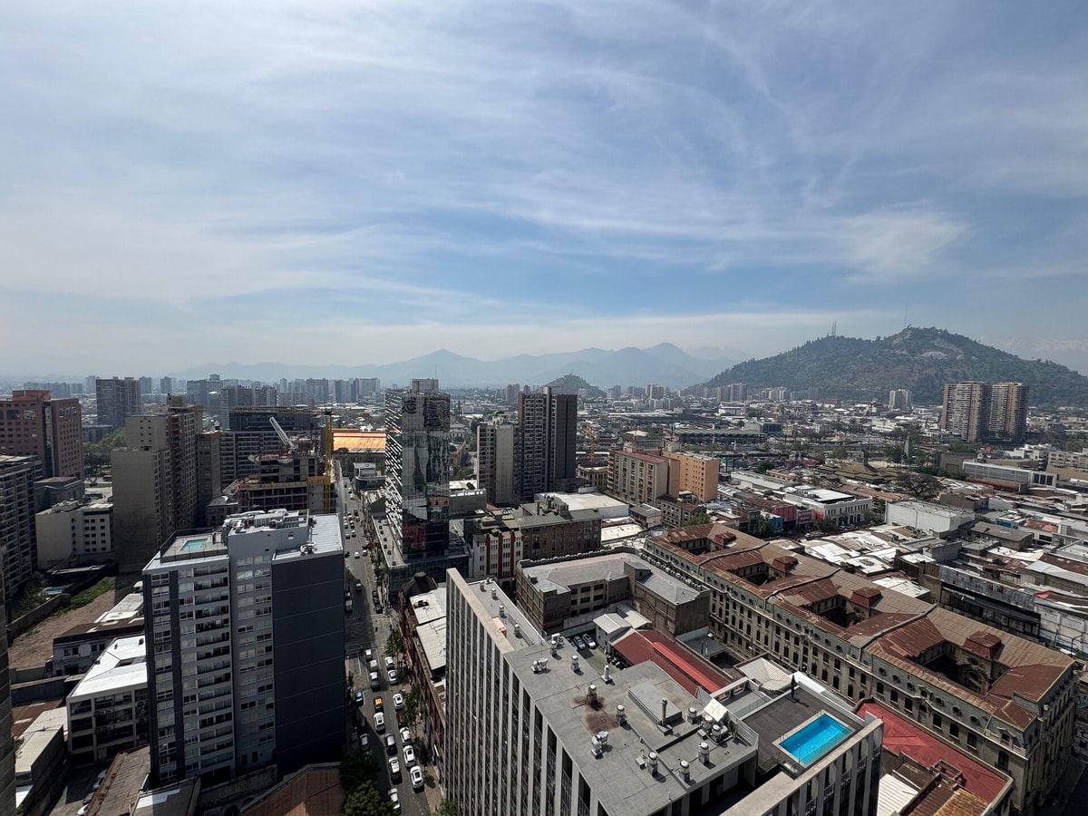 Vista panorámica del centro de Santiago desde la altura, con el cerro Santa Lucía, los techos del barrio y la cordillera al fondo