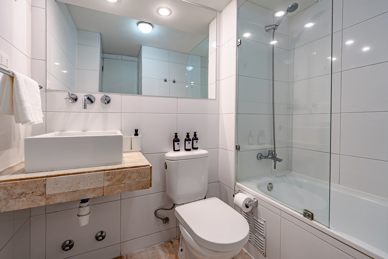 Baño con lavamanos flotante de madera, ducha con mampara y toallero