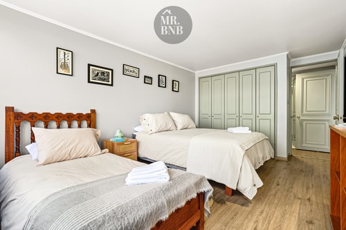 Dormitorio con dos camas individuales y puertas de clóset verde oscuro