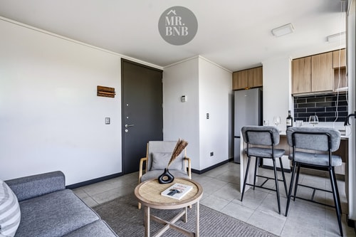 Living comedor con sillón, mesa de centro y barra de cocina al fondo