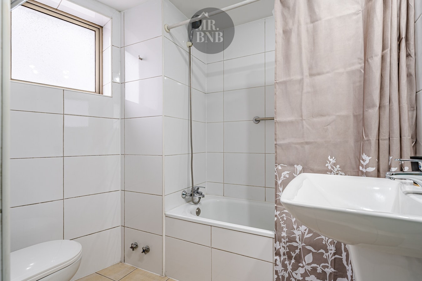 Baño con tina, cortina floral, lavamanos y ventana